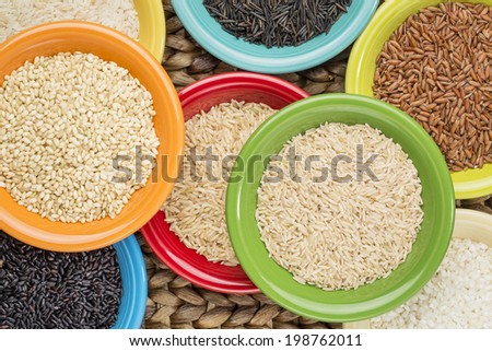 a variety of rice grains on colorful ceramic bowls against a woven water hyacinth mat