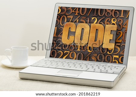code word in vintage letterpress wood type against number background on a laptop computer with a cup of coffee