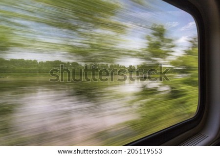 blurred abstract landscape of Missouri River seen from a train window in motion
