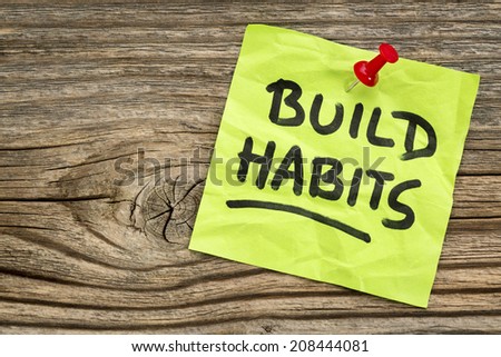 build habits reminder - self-development concept - handwriting on a green sticky note against grained and knotted wood board