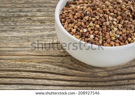 roasted buckwheat grain (kasha) in a small white bowl against grained wood