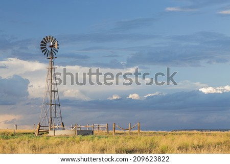 windmill with a pump  and cattle water tank in shortgrass prairie, Pawnee National Grassland in Colorado near Grover