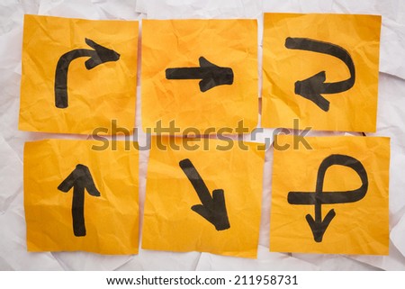 confusing directions concept - a variety of arrows on crumpled, orange sticky notes