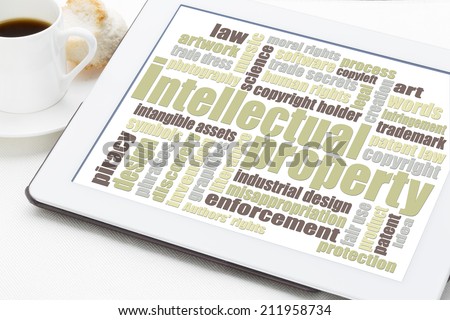 intellectual property word cloud on a digital tablet with a cup of coffee