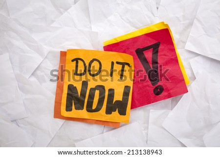 do it now reminder - colorful sticky notes on a background of crumpled white notes