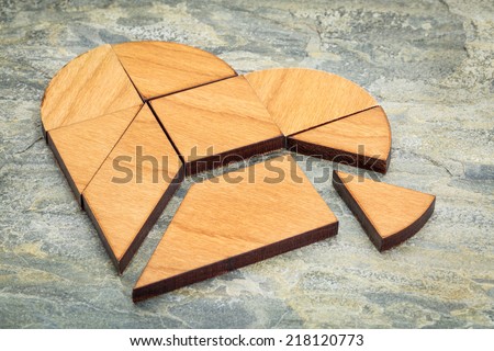heart version of tangram, a traditional Chinese Puzzle Game made of different wood parts to build abstract figures from them, on  a slate rock background