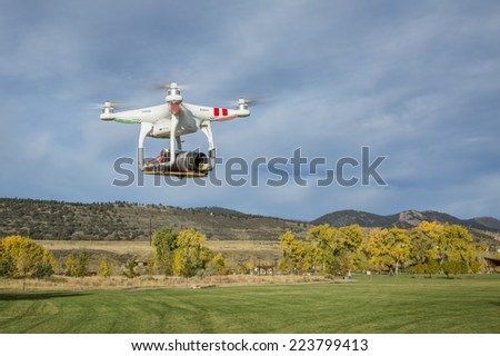 FORT COLLINS, CO, USA, October 15, 2014:  Airborne radio controlled Phantom quadcopter drone flying over park at foothills with a camera mounted on a home made platform.