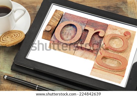 dot org internet domain for non-profit organization in letterpress wood type printing blocks on a digital tablet screen with a cup of coffee