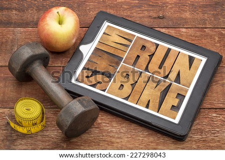run, bike, swim - fitness or triathlon concept - word abstract in letterpress wood type on a digital tablet with a dumbbell, apple and tape measure