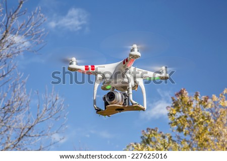 FORT COLLINS, CO, USA, November 1, 2014:  Airborne radio controlled Phantom 2 quadcopter drone flying over trees with  the Panasonic Lumix GM1 camera mounted on a home made platform.