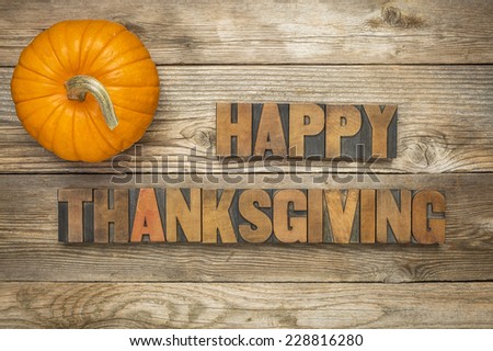 Happy Thanksgiving  - text in vintage letterpress wood type blocks against rustic wood background with a pumpkin