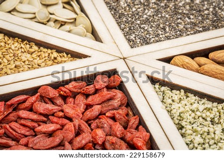 superfood abstract - dried goji berries, golden flax, pumpkin seeds, almonds, chia seeds and hemp seed hearts on a wooden tray
