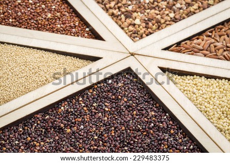 variety of gluten free grains (red and black quinoa, buckwheat, brown rive, amaranth and millet) in a wooden tray, focus on black quinoa