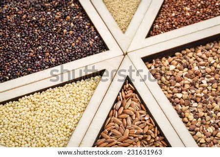 variety of gluten free grains (red and black quinoa, buckwheat, brown rive, amaranth and millet) in a wooden tray, focus on millet and rice