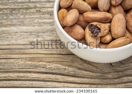 bowl of raw organic cacao beans  against grained wood