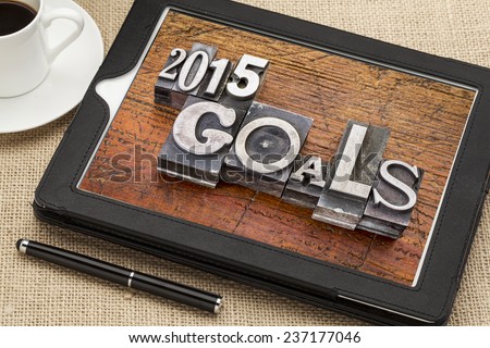 2015 goals - New Year resolution concept - text in vintage metal type blocks against grunge wood on a digital tablet with a cup of coffee