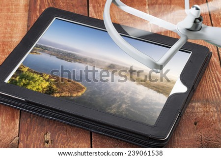 drone aerial photography concept - reviewing aerial pictures of a foggy lake on a digital tablet with a drone rotor, screen picture created by the photographer