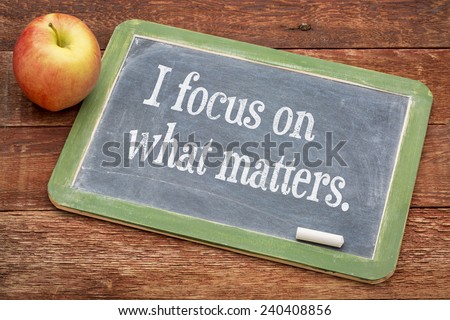 I focus on what matters - positive affirmation words on a slate blackboard against red barn wood