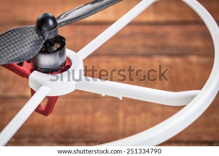 a detail of drone electric motor, carbon fiber propeller and propeller guard over wood background