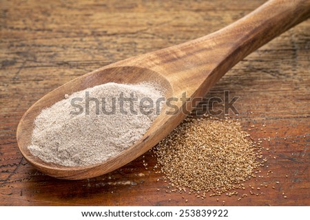 teff grain and flour i- a wooden spoon against grained wood background