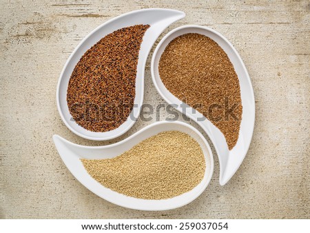 three tiny gluten free grains - kaniwa, amaranth and teff on teardrop shaped bowls against white painted rustic wood