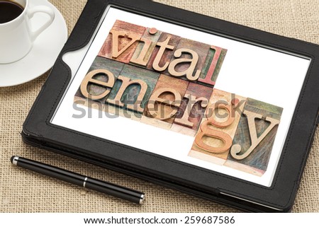 vital energy typography - text in letterpress wood type blocks on a digital tablet with cup of coffee