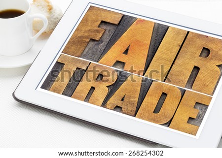 fair trade word abstract typography -  text in letterpress wood type on a digital tablet with a cup of coffee