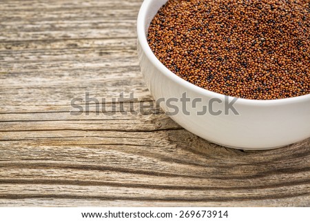gluten free kaniwa grain (also known as baby quinoa) in a small ceramic bowl against grained wood