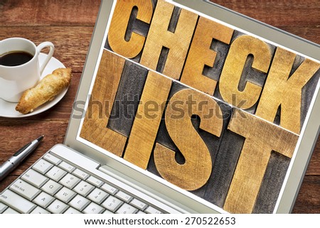 checklist word typography - isolated text in letterpress wood type on a laptop with a cup of coffee