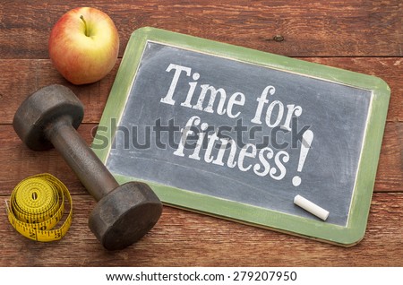 stay in shape concept -  slate blackboard sign against weathered red painted barn wood with a dumbbell, apple and tape measure