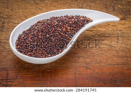 gluten free black quinoa grain grown in Bolivia ,  a teardrop shaped bowl against rustic grunge wood with a copy space