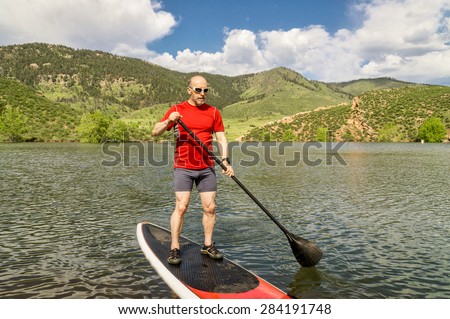 male paddler enjoying stand up paddling on a sunny summer day - Horsetooth Reservoir, Fort Collins, Colorado