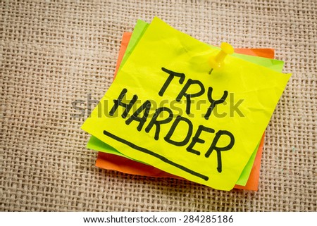 try harder - motivation words on a  yellow sticky note against burlap canvas