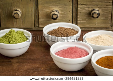 super fruit and leaf powders in small ceramic bowls - baobab, noni, yumberry, moringa, mangosteen