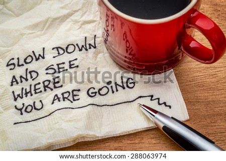 slow down and see where you are going - motivational reminder - handwriting on a napkin with a cup of coffee