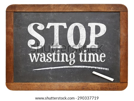 Stop wasting time sign - white chalk text on a vintage slate blackboard