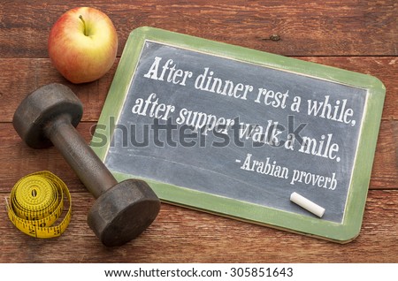 After dinner rest a while, after supper walk a mile -  Arabic proverb on a slate blackboard sign against weathered red painted barn wood with dumbbell, apple and tape measure - healthy living concept