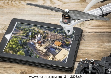 drone aerial photography concept - reviewing aerial picture of grain elevators  on a digital tablet with a drone rotor and radio control transmitter,