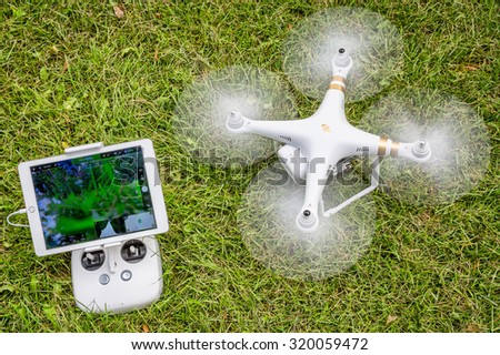 FORT COLLINS, CO, USA - AUGUST 28, 2015:  Spinning propellers and getting ready to take off. DJI Phantom 3 hexacopter drone with radio controller and iPad Air on grass area.