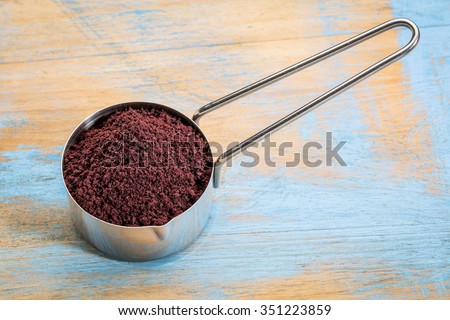 acai berry powder on a metal measuring scoop against painted grunge wood