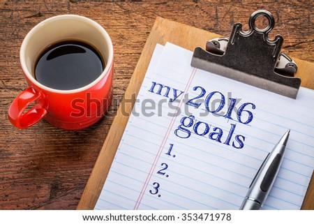 my 2016 goals list on clipboard and coffee against grunge wood desk