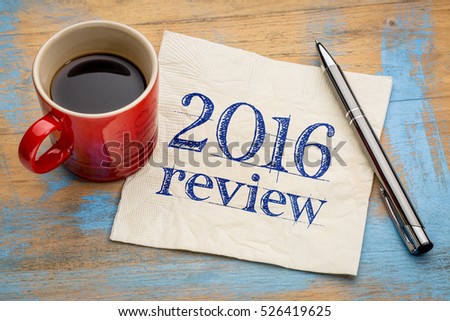 2016 review text on a napkin with coffee against grunge wood desk