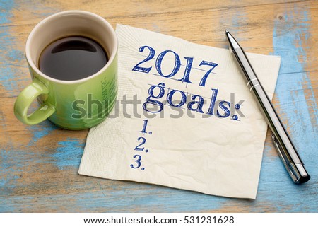 2017 goals list on a stained napkin against grunge wood table with  a cup of coffee
