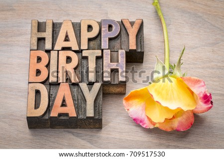 Happy Birthday greeting card in vintage letterpress wood type against grained wood with a rose