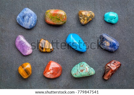 set of polished, semiprecious, colorful gemstones against gray slate stone