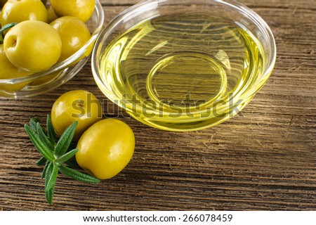 Green marinated olives, olive oil on a wooden table