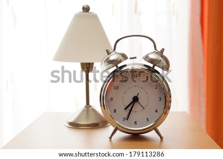 Silver alarm clock with night lamp on bedside cabinet