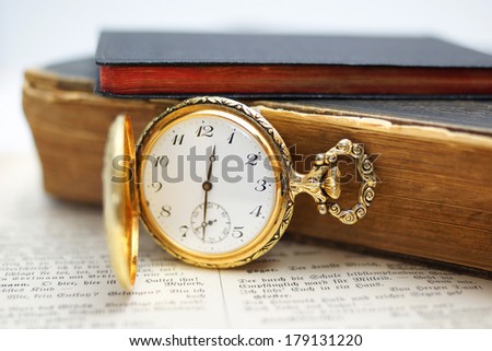 old gold pocket watch with old books