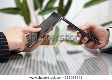 woman and man transferring files from smart mobile phone to another
