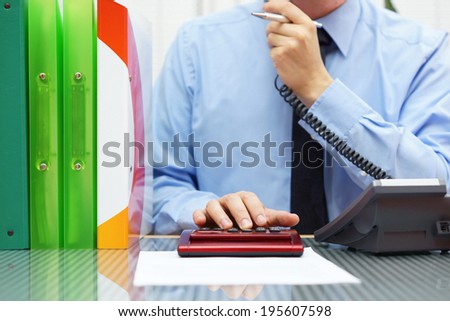 very busy advisor on the  phone and working on calculator with a lot of paperwork